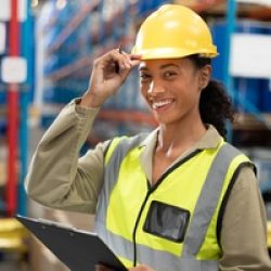 Female staff looking at camera while holding clipboard in wareho