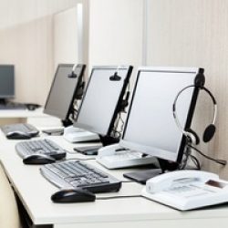 Row of computers with headphones on desk at corporate office