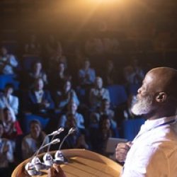 Businessman standing near podium and giving speech to the audien
