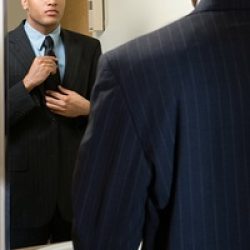 Man adjusting his tie in mirror